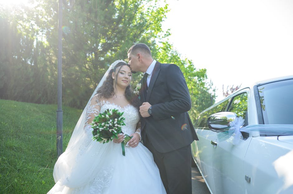 Bride and groom sharing a tender moment by a limousine in a lush outdoor setting.